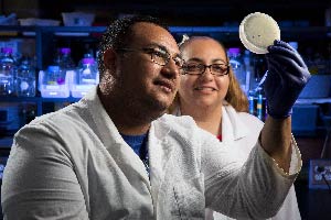 Two students in labcoat looking at a sample