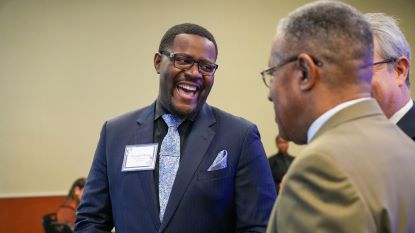 Scholarship recipient laughs while speaking with President Blanchard, among others